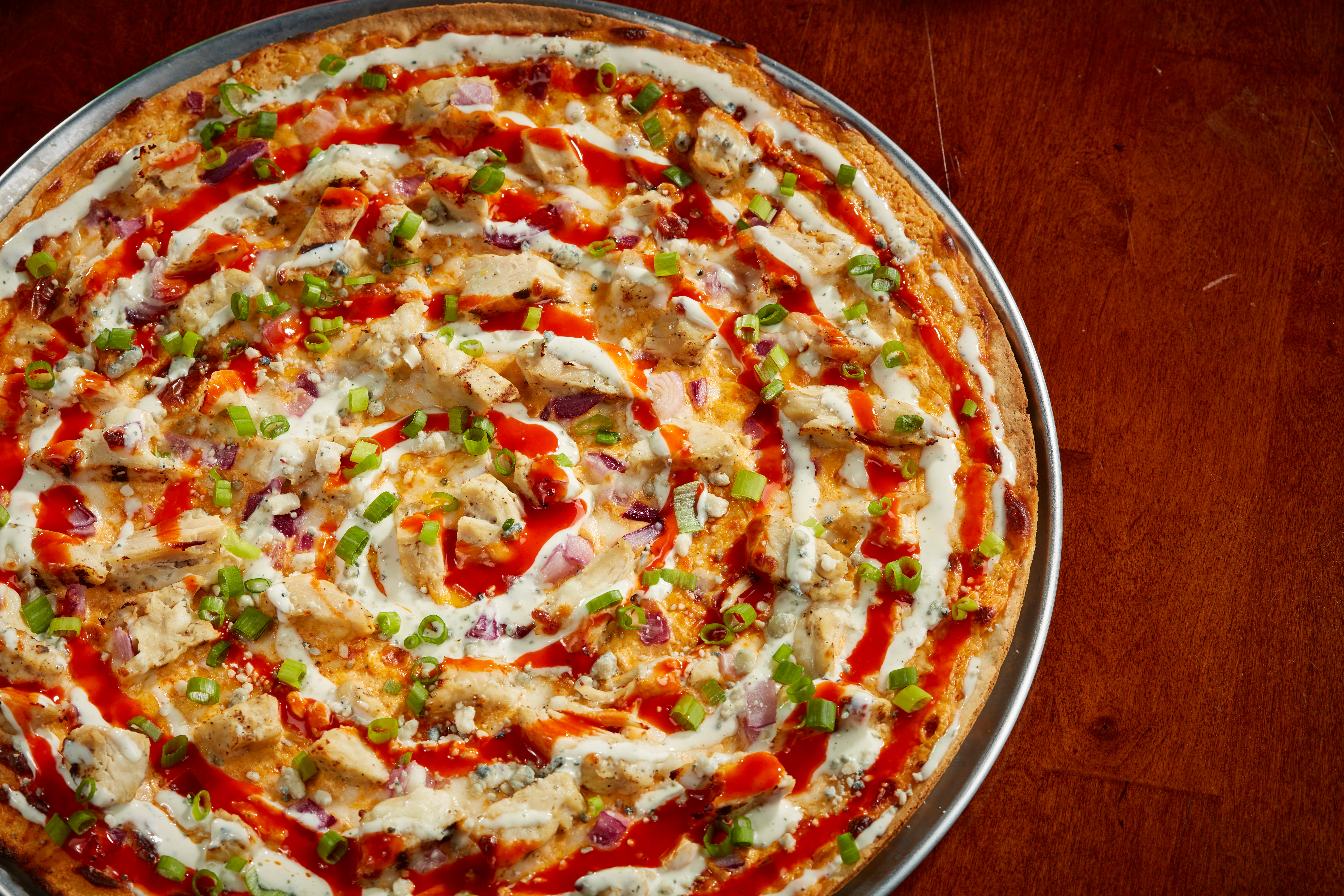 Our thin crust with house-made buffalo cheese sauce, grilled chicken, sliced red onion, mozzarella and blue cheese, topped with green onion, buffalo sauce and ranch dressing. $22.99