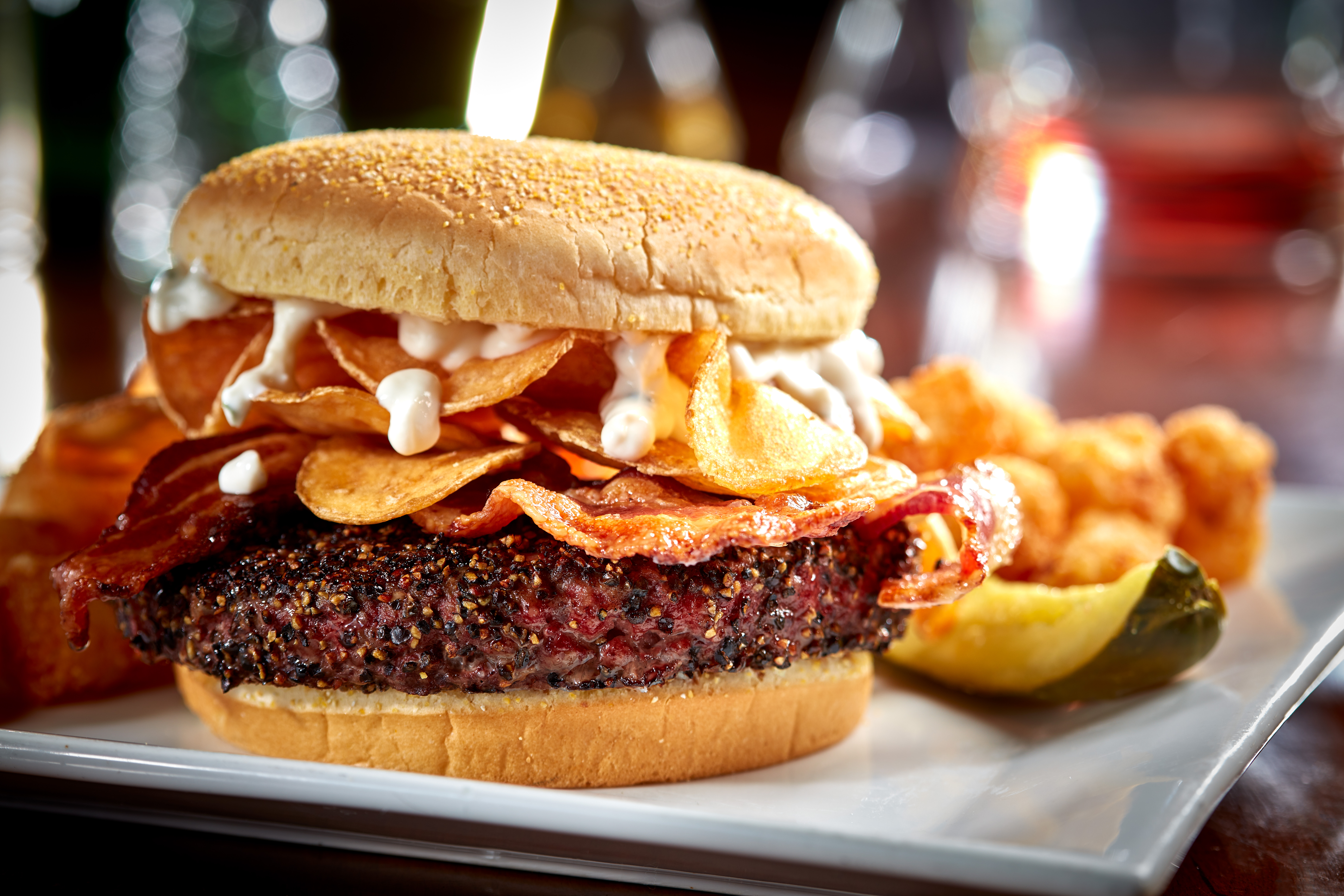 Black peppercorn crusted burger topped with double smoked bacon, house fried pub chips and garlic-chive aioli. $15.99