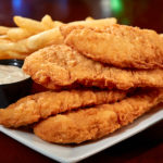 Chicken tenders on a plate with fries and dip